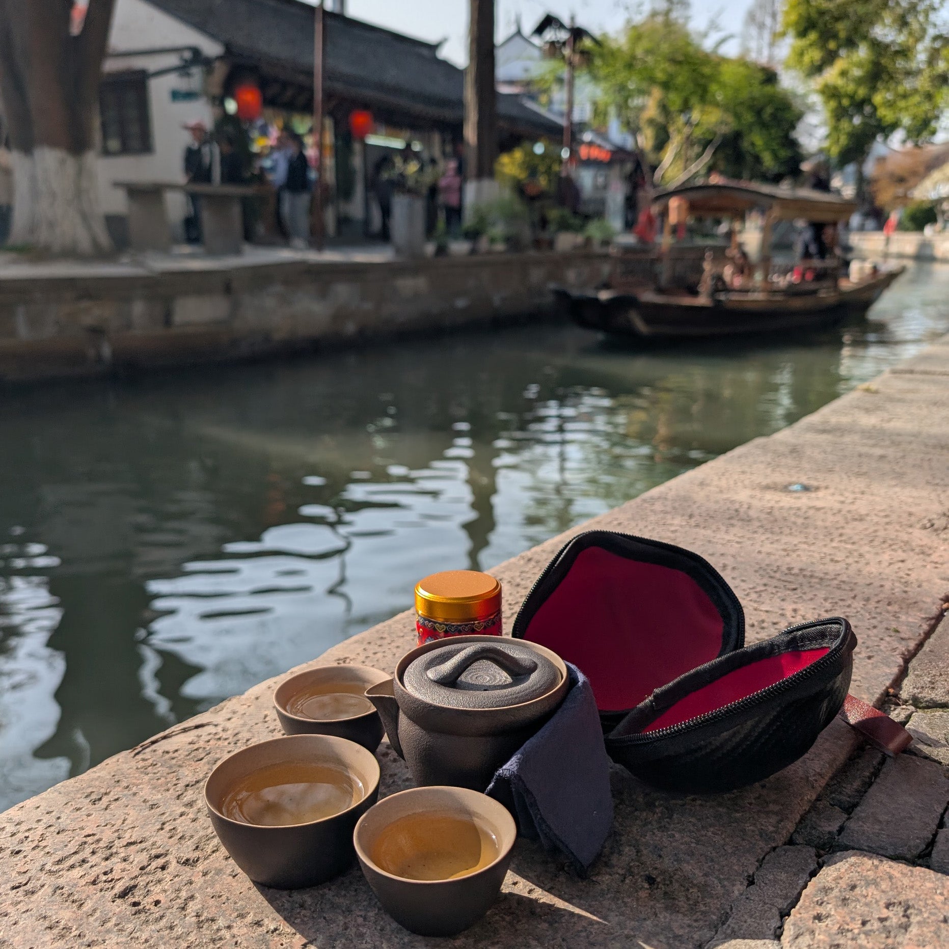 Eco-Cha Travel Tea Set  on a stone ledge overlooking a picturesque canal in an old Chinese village with a old-style wooden boat floating by.