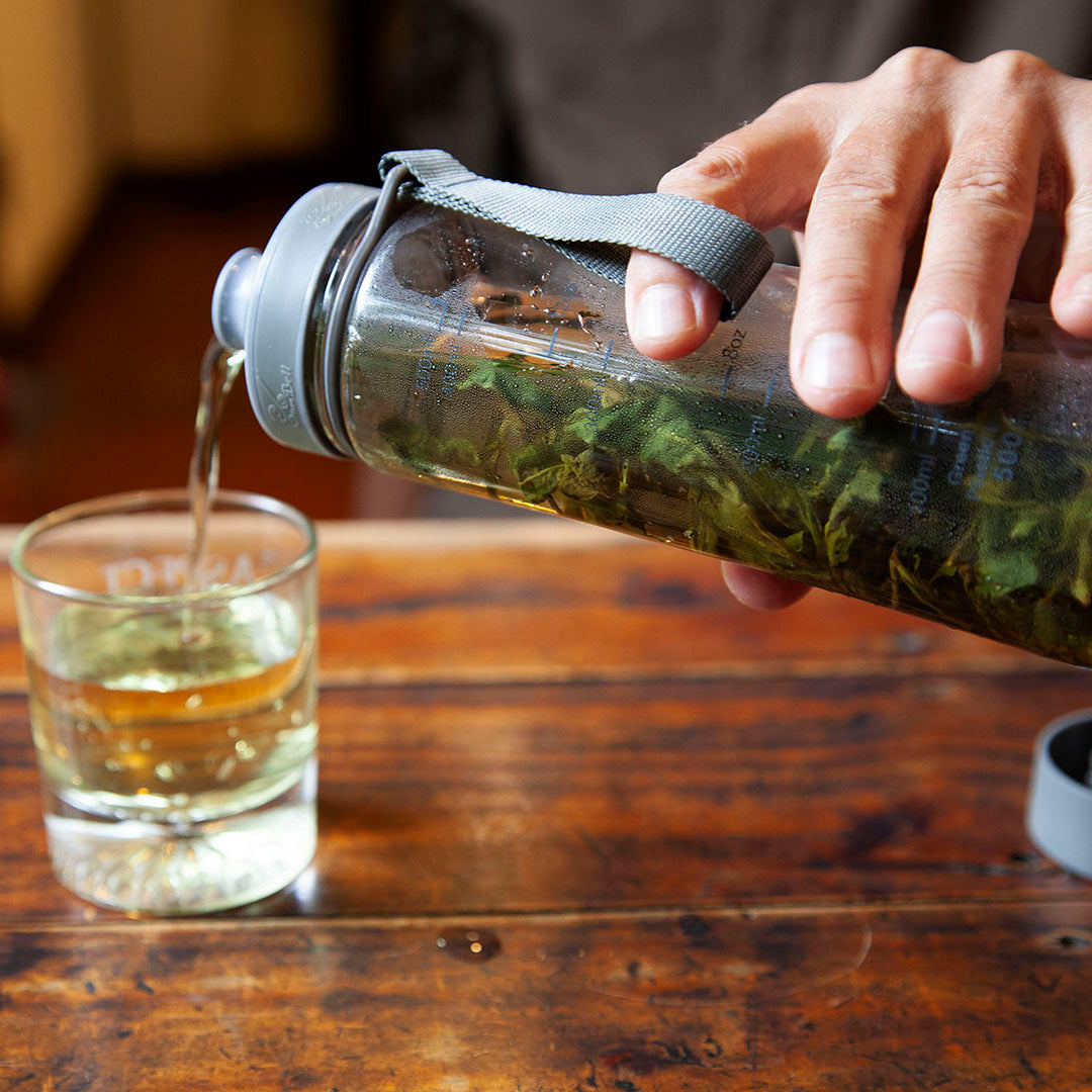 Eco-Cha Teas cold brew bottle pouring out some cold brewed tea into a glass cup.