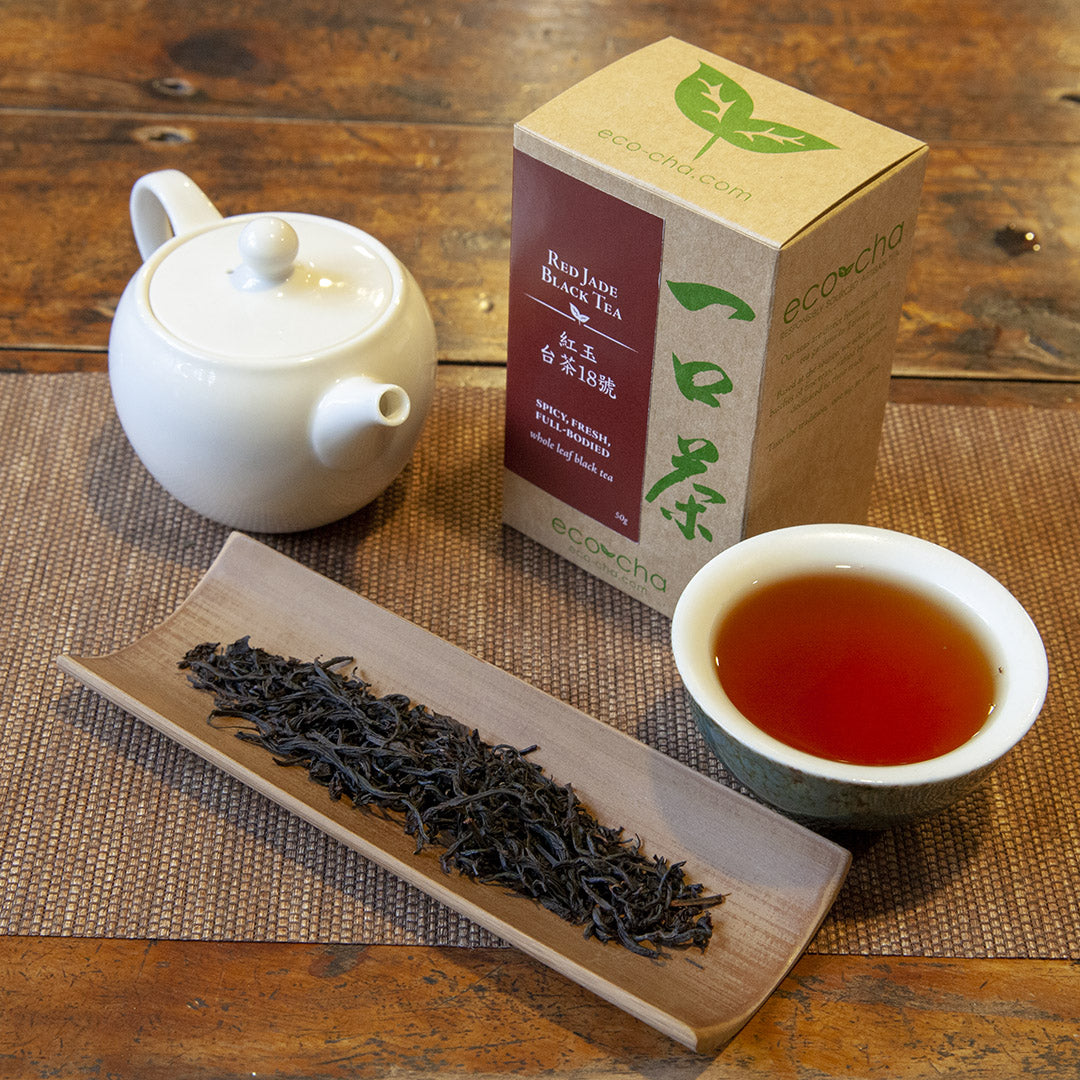 Red Jade Black Tea on table in cup with white teapot and package