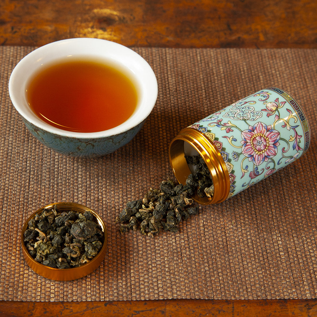 Blue ceramic tea caddy with tea leaves and brewed tea