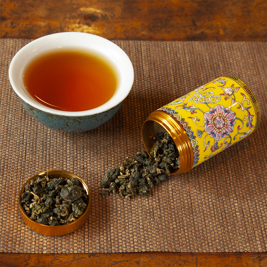 Yellow ceramic tea caddy with tea leaves and brewed tea