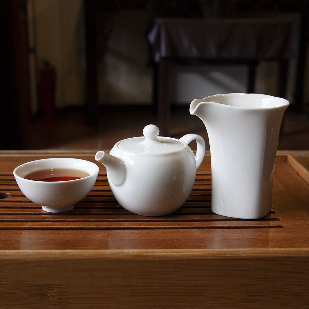 White porcelain pitcher with cup and teapot on tea tray