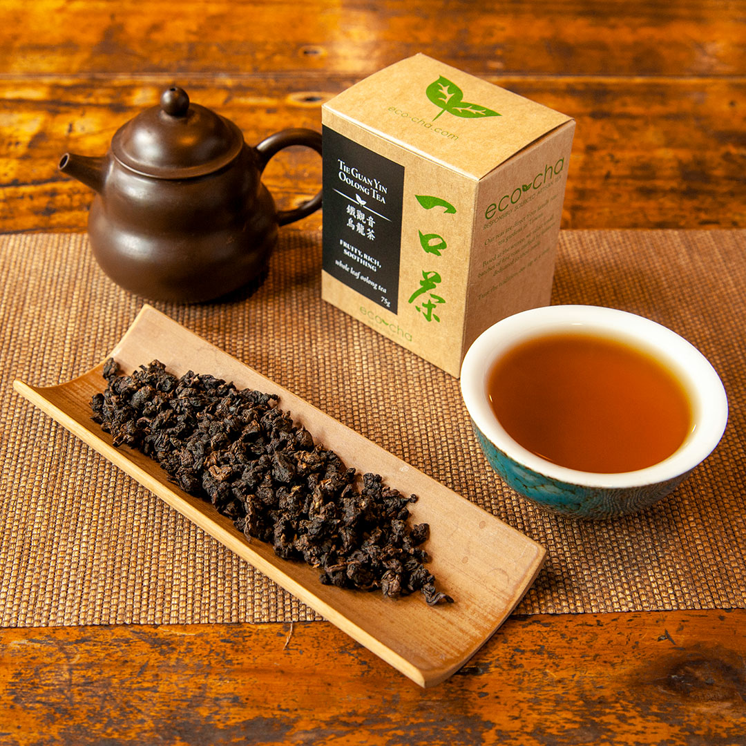 Tie Guan Yin Oolong Tea in teacup on wooden table next to packaging