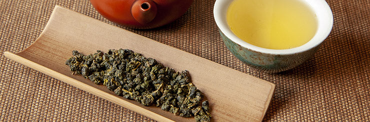 Alishan High Mountain Oolong Tea leaves with cup and pot