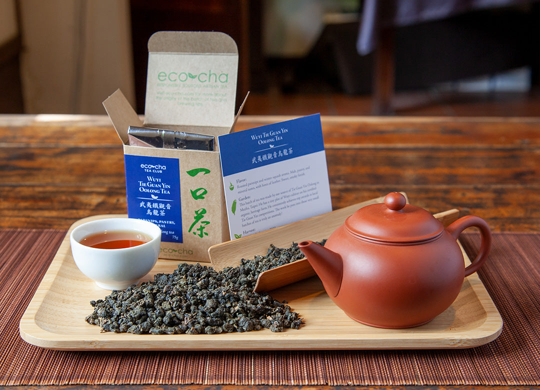 Tea leaves on a tray with tea pot and brewed tea