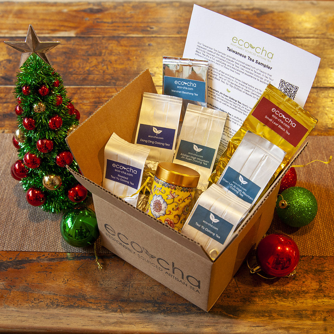 Eco-cha Tea Sampler box with tea bags, a yellow ceramic tea caddy, and decorative items on a wooden surface.