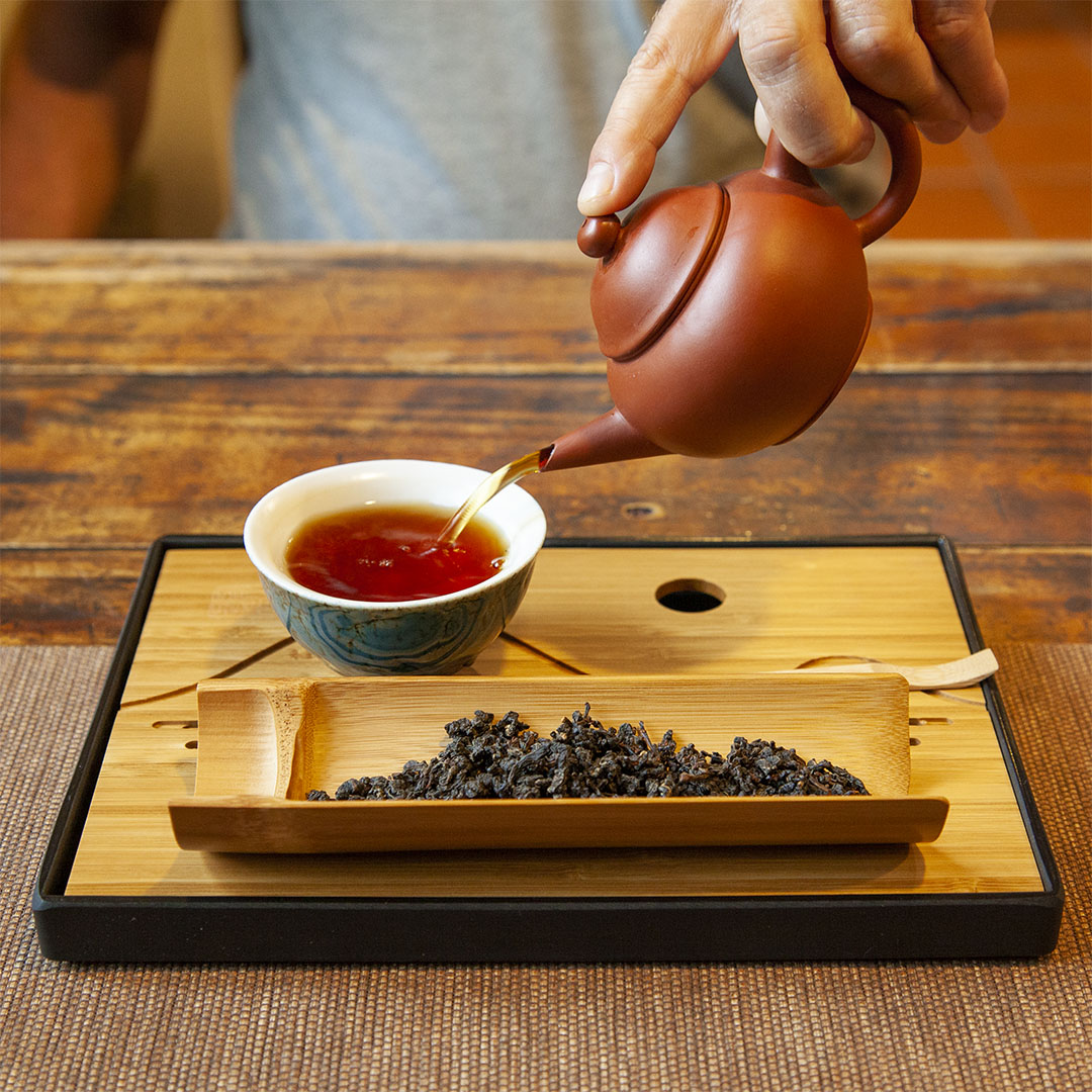 Bamboo tea tray with cup of tea and dry tea leaves