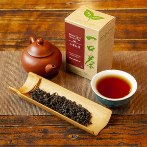 Small Leaf Black Tea in teacup on table with packaging and dry leaves