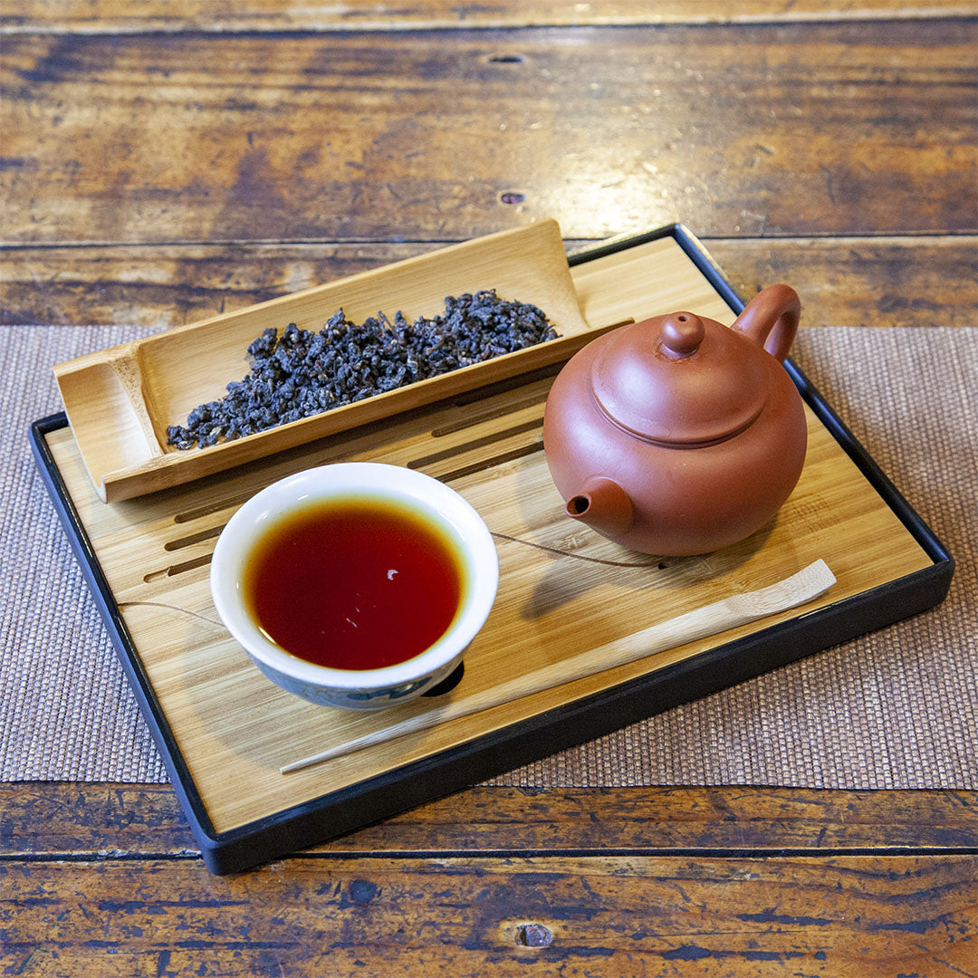 Portable bamboo tea tray with full tea cup, dry tea leaves and tea pot