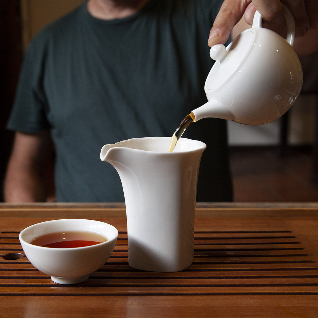 Pouring tea into white porcelain tea pitcher